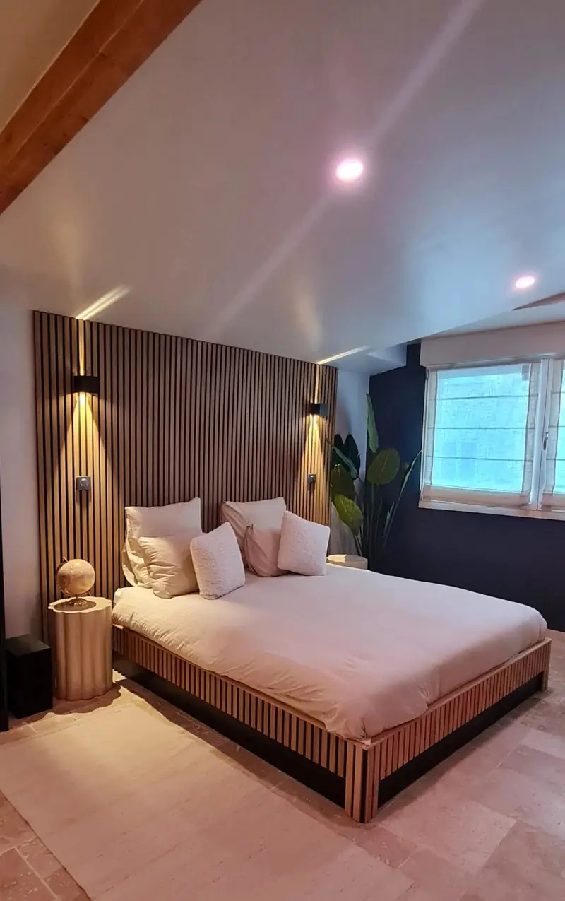 Chambre avec tête de lit et habillage mural en tasseaux de bois