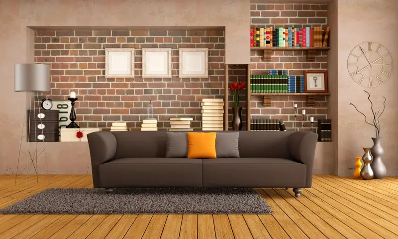 Salon avec canapé gris, mur de briques et bibliothèque